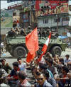 A Nepalese Army armoured vehicle passes by protestors staging a sit-in protest rally on the 16th day of a general strike at Kalanki in Kathmandu